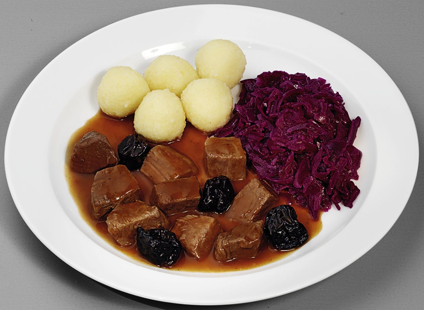 Zartes Gulasch vom Hirsch  in feiner Rotweinsoße mit Pflaumen, dazu Rotkohl und Kartoffelklöße